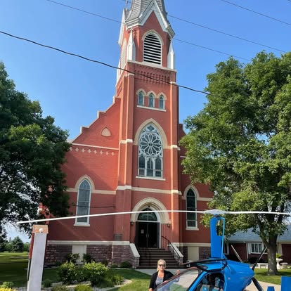 A tall, red-brick church tower with a clock and clear blue sky.