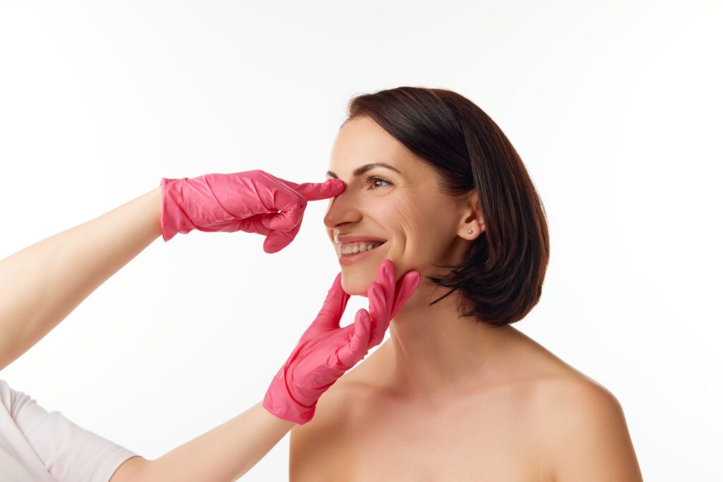 Woman wearing pink gloves pinching her nose.
