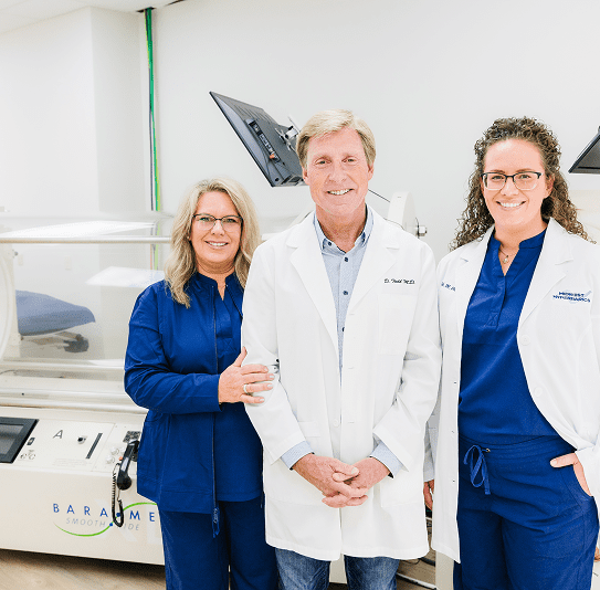 Three scientists in lab coats posing in a laboratory.