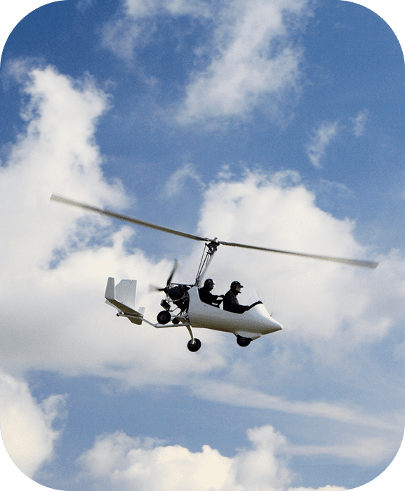 A person flying a motorized hang glider under a partly cloudy sky.