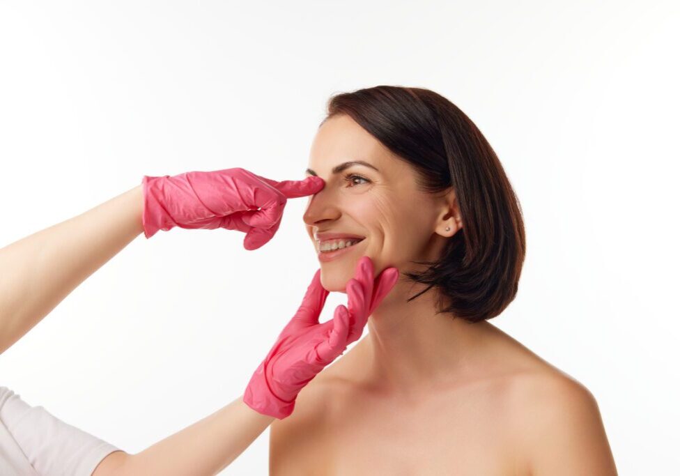 Woman wearing pink gloves pinching her nose.